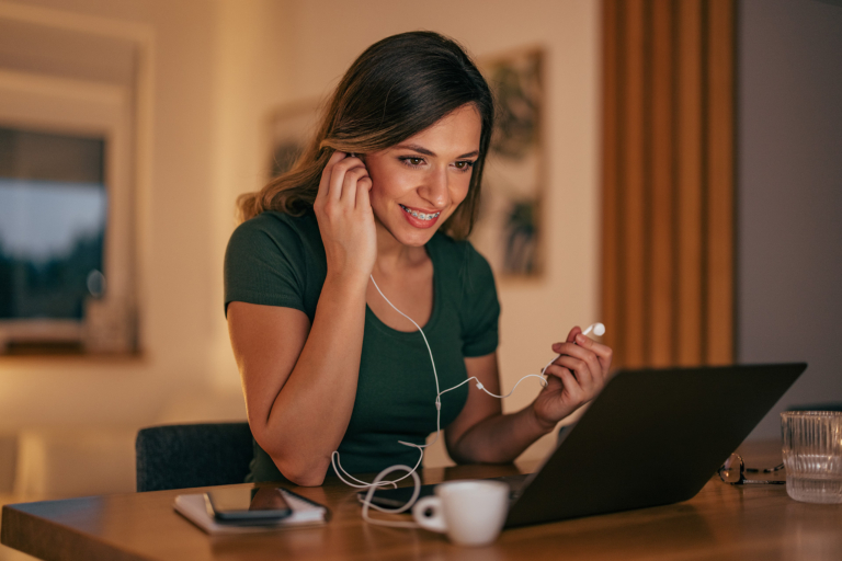 Woman using headphones while viewing laptop