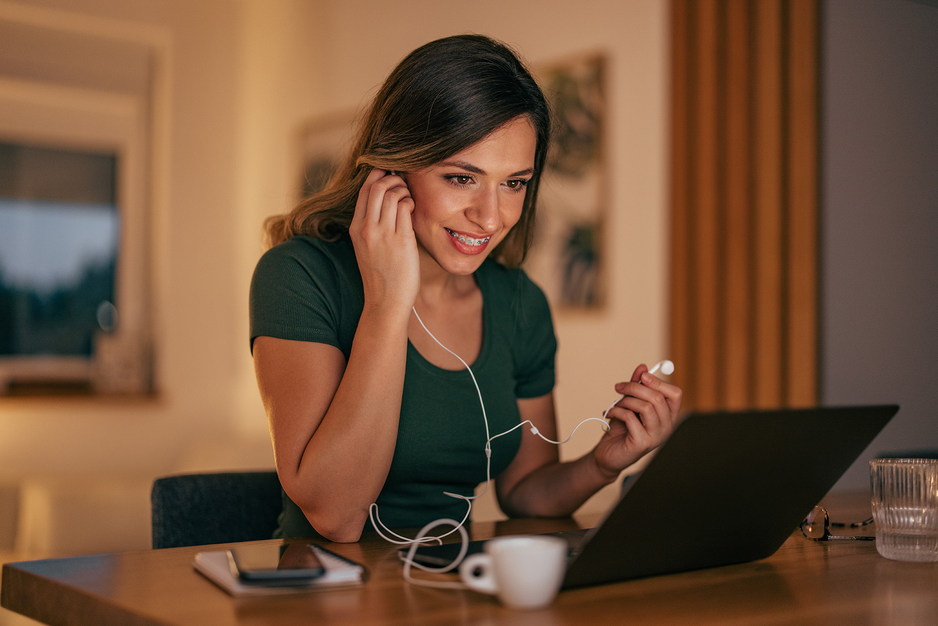 Woman using headphones while viewing laptop
